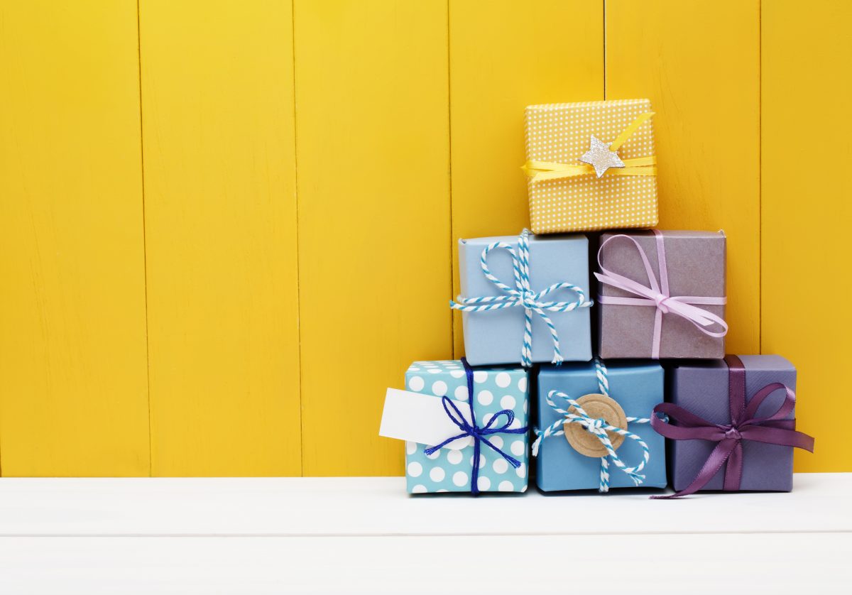 Stack of little present boxes on yellow wooden wall