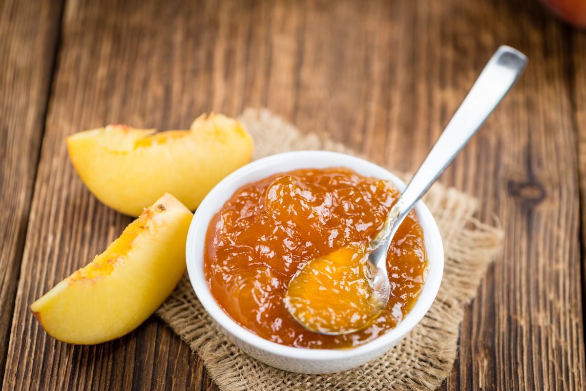 Fresh made Peach Jam (close-up shot; selective focus) on wooden background